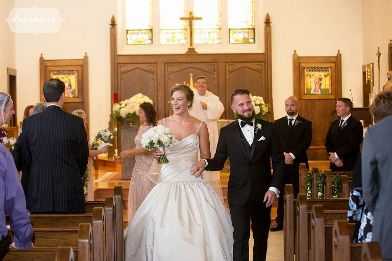 Bride and groom happily walk out of ceremony at St. Denis in Windsor, VT.