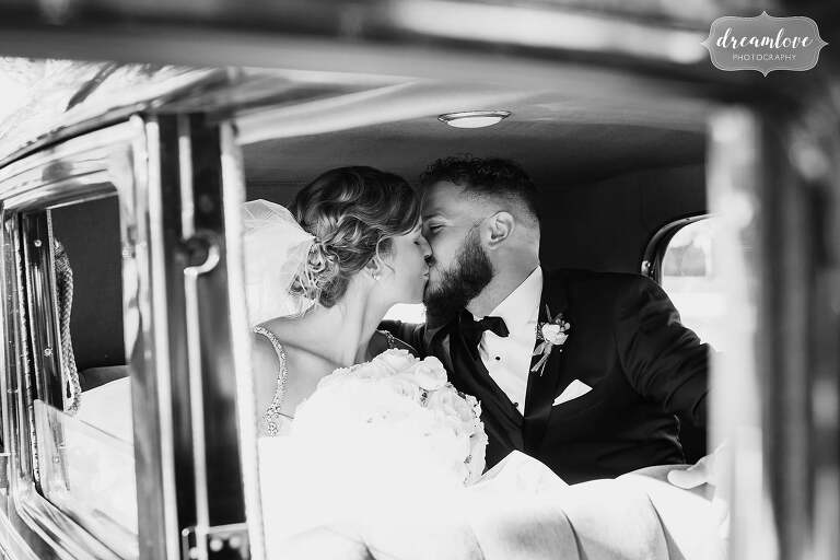 The bride and groom kiss inside of an antique car in Windsor, VT.