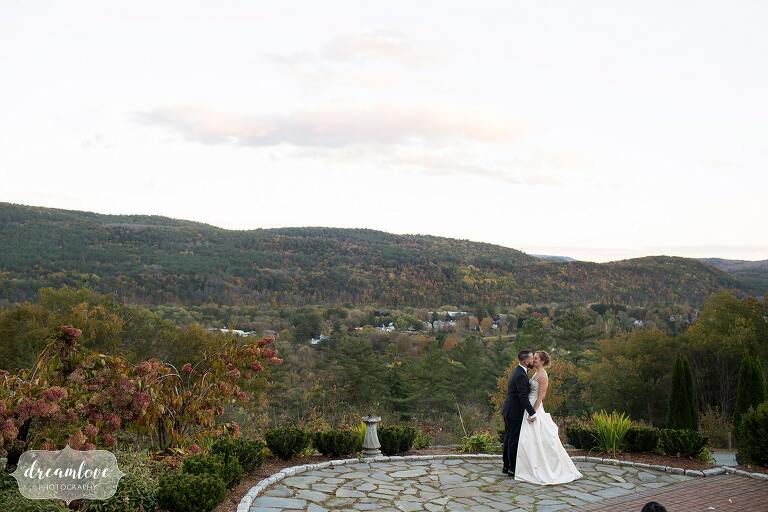 Bride and groom pose in front of green mountains at the Windsor Mansion venue.