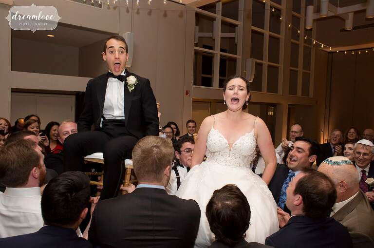 The bride and groom are lifted up on chairs during tradition hora dance at Temple Shir Tikva.