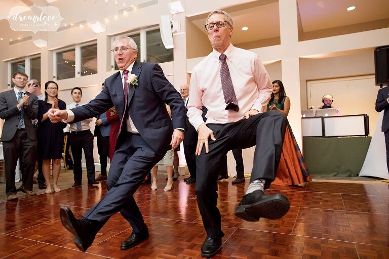 Two men do a traditional Jewish wedding dance kicking legs up in Boston.