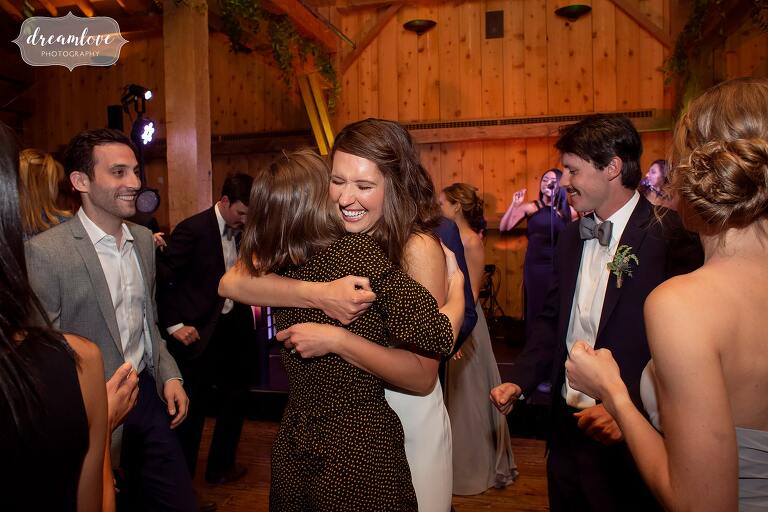 Bride hugs friend on dance floor at Devil's Thumb Lodge wedding.