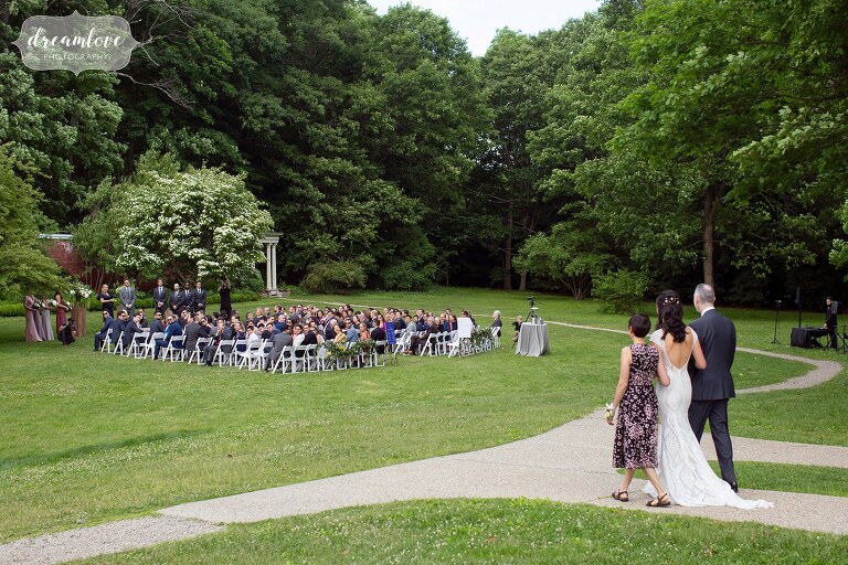 Bride walks into garden ceremony with parents at Lyman Estate.