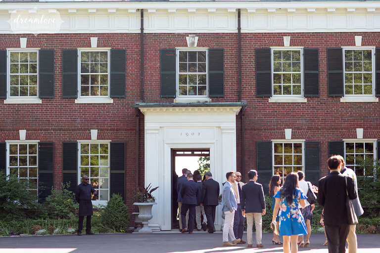 Guests mingle in front of brick wedding estate mansion on south shore.