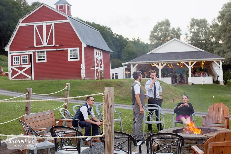 Guests sit around bonfire pit at Warfield House Inn wedding in Charlemont, MA.