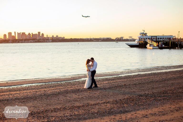 Warm toned sunset bride and groom kiss on Boston beach.