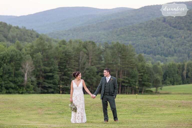 Bride and groom hold hands in front of Berkshire Mountains.