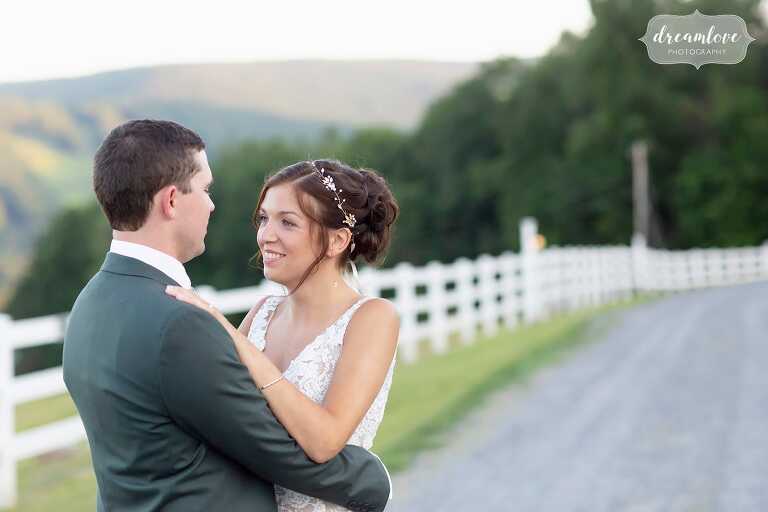 Bride and groom stand next to horse fencing at western Mass wedding.