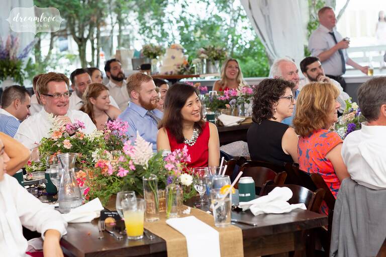 Guests laugh during speeches at outdoor Warfield House Inn wedding.