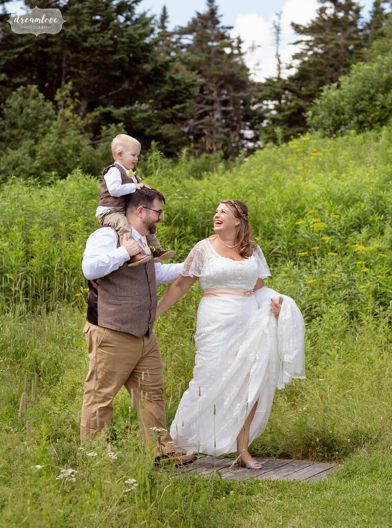 Family walks through green field before their mountaintop wedding at Mt. Greylock.