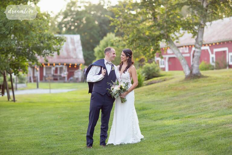Bride and groom pose for their NH barn wedding at Bishop Farm with Bishop Farm dairy barns behind them.