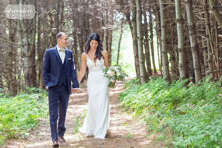 Bride and groom walk through pine forest at Bishop Farm.