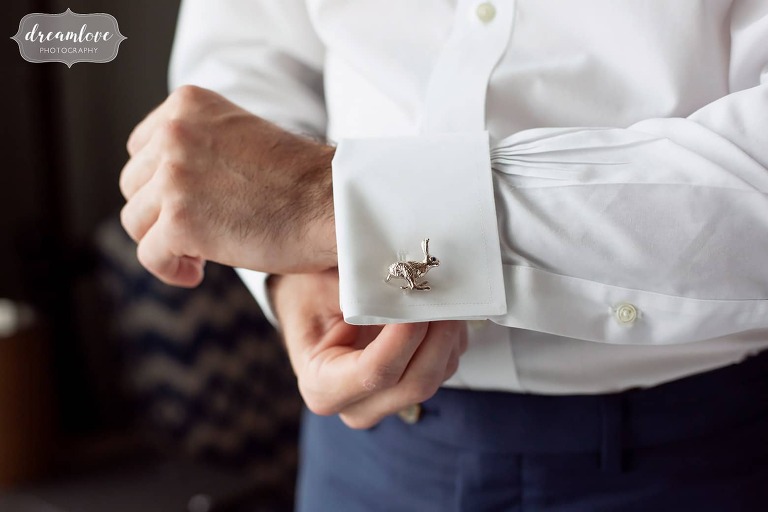 Groom puts on his silver rabbit cufflinks at Beauport Hotel.