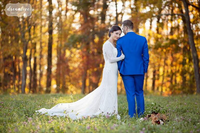 Bride wraps her arms around groom with bright fall foliage at Zukas Barn.