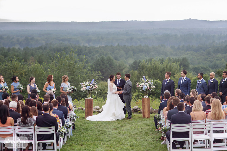 Bride and groom stand in outdoor ceremony at Fruitlands Museum wedding venue with stunning scenic views.