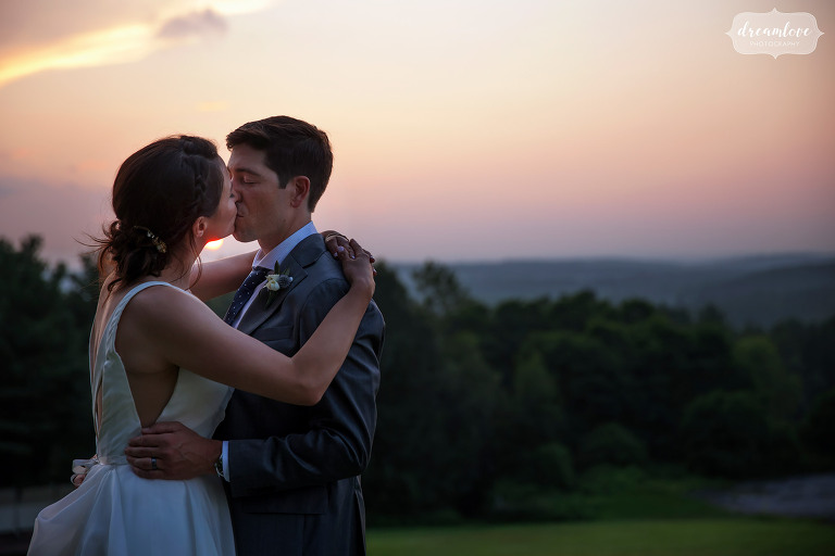Fruitlands Museum wedding bride and groom kiss with sunset in background.