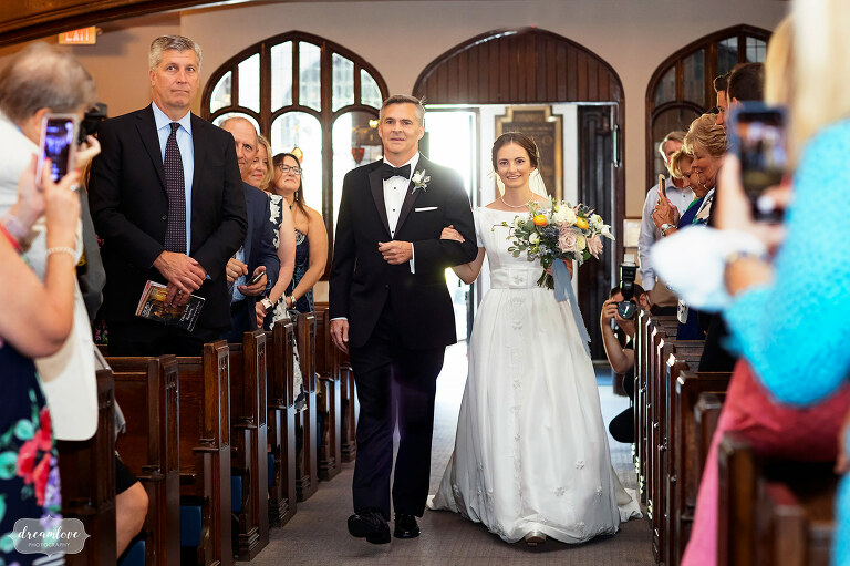 Bride and her father walk down the aisle at Sacred Heart church in Manchester, MA during wedding.