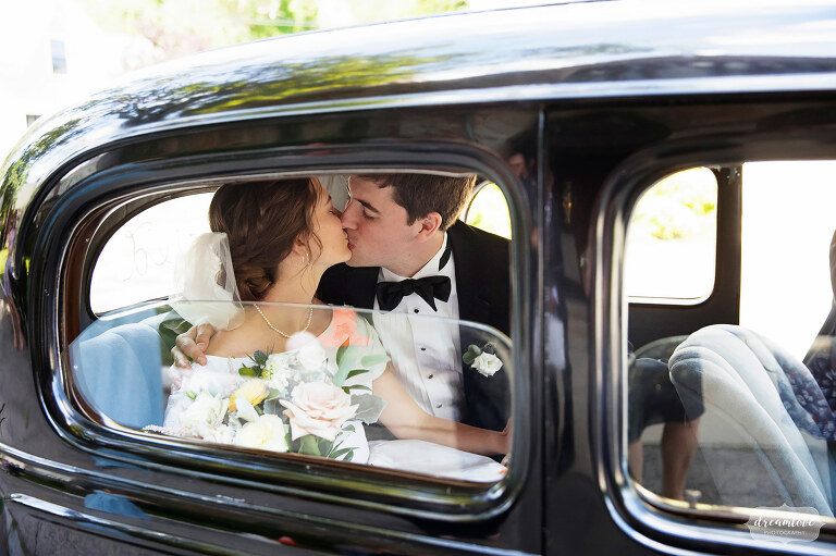 Bride and groom kiss in back of 1930's Chevy in Manchester, MA.
