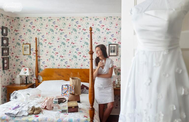 Bride looks past four post bed at the Brick House at Shelburne Farms.