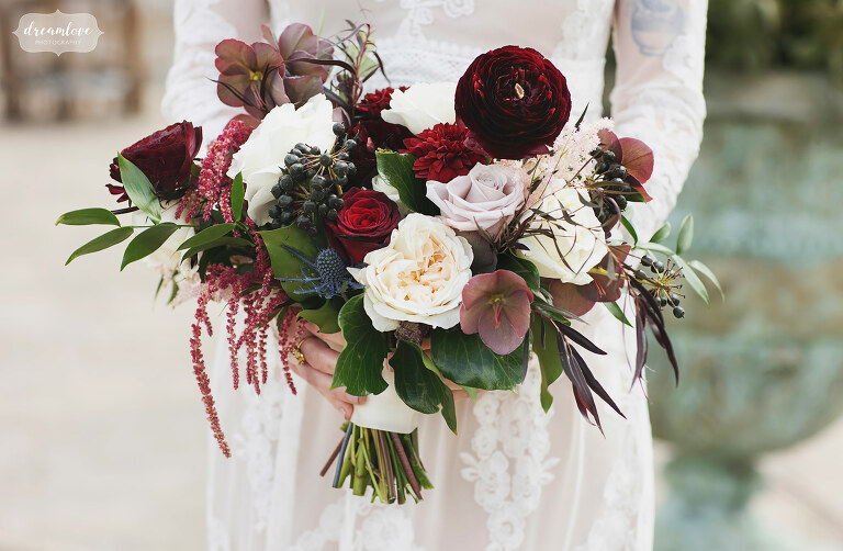 Beautiful jewel tone wedding bouquet with maroon and greenery.