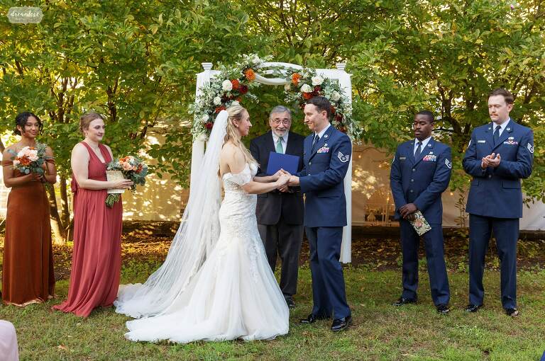 Bride and groom hold hands during outdoor ceremony at Deerfield Inn.