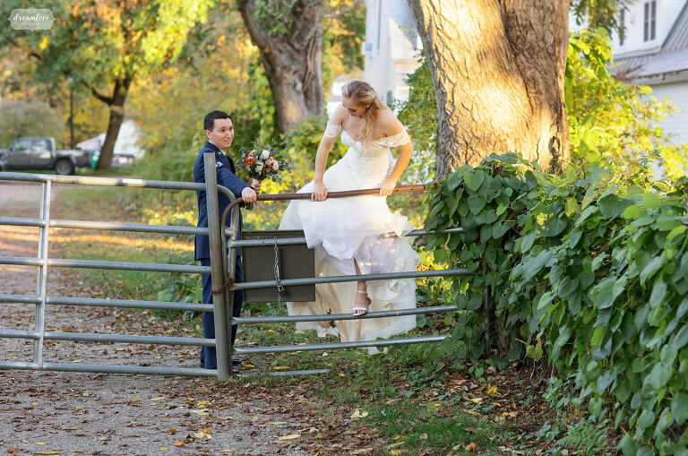 Funny photo of bride climbing a livestock fence at the Deerfield Inn in MA.