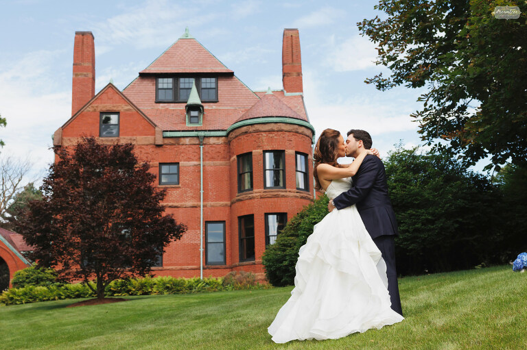 Bride and groom kiss in front of brick mansion estate wedding venue near Boston.